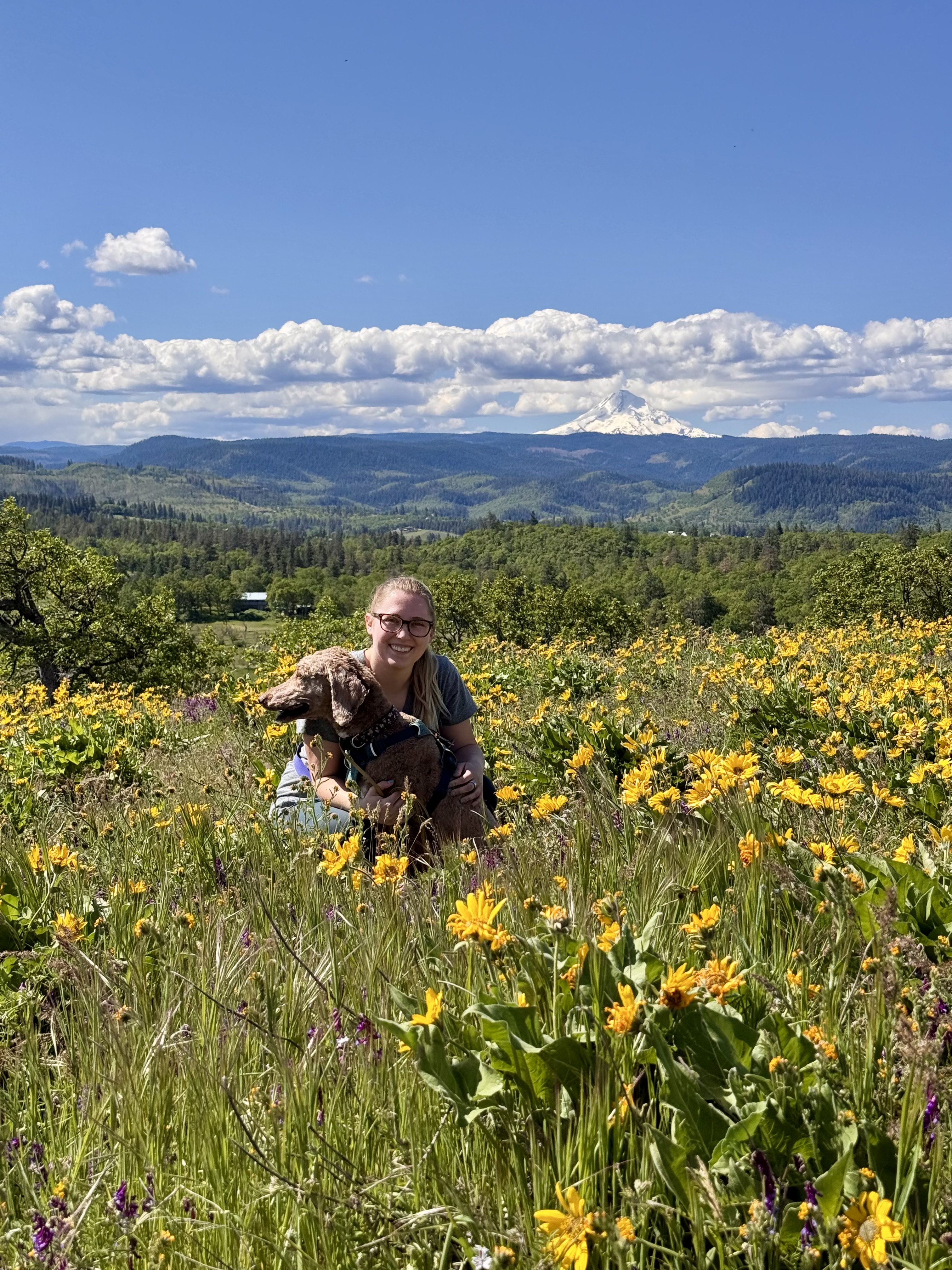 Bailey Sumner with a dog in a wildflower meadow in the Pacific Northwest